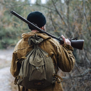  A man carrying rifle and backpack