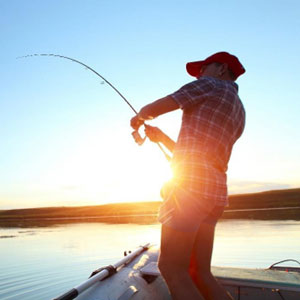 A man fishing on a boat at sunset, enjoying the tranquil beauty of nature's colors reflecting on the water.